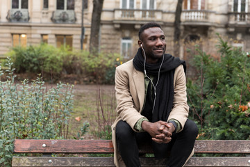 Obraz premium Handsome Black Man Sitting on Public Park Bench Backrest