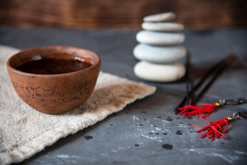 A bowl of tea on a linen towel, with a pyramid of stones in the background.