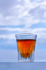 A beautiful glass of whiskey is on the ice. Orange alcoholic drink in a glass. Copy space. Side view. Vertical.