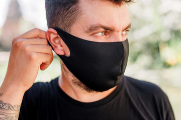Young man wearing a protective mask on green background. Protection against contagious disease, coronavirus. Hygienic mask to prevent infection, airborne respiratory illness such as flu, 2019-nCoV.