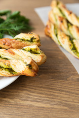 salty sticks of puff pastry sprinkled with cumin and greenery on a wooden background