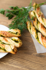 salty sticks of puff pastry sprinkled with cumin and greenery on a wooden background