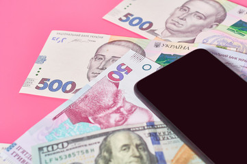 Smartphone and different money on pink background. Concept of mobile banking. Online shopping from home. Distancing control financial balance