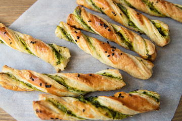 salty sticks of puff pastry sprinkled with cumin and greenery on a wooden background