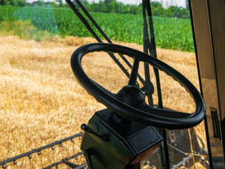 Wheat harvesting in the summer. View from the cab of the combine on the field of shnitsy. Golden ripe wheat harvest agricultural machine harvester on the field.