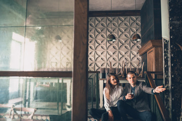 Cheerful caucasian man and woman talking, enjoying at the alco shop, cafe, bar. Couple or friends, having a date, romantic. Wearing casual attire. Emotional, smiling. Communication, relations concept.