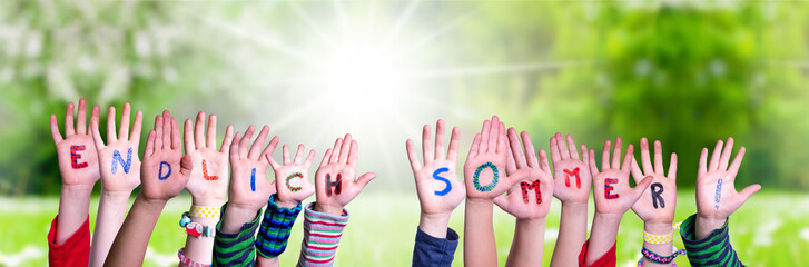 Children Hands Building Colorful German Word Endlich Sommer Means Finally Summer. Green Grass Meadow As Background