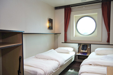 Oceanview cabin or exterior or outside stateroom with two single beds and large porthole in...