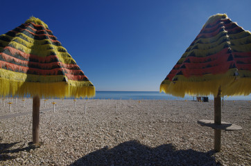 Two umbrellas open on a pebble beach