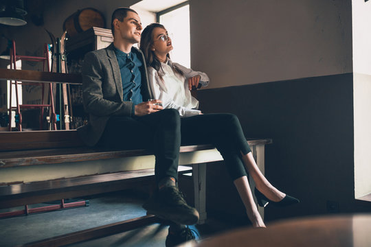 Cheerful caucasian man and woman talking, enjoying at the alco shop, cafe, bar. Couple or friends, having a date, romantic. Wearing casual attire. Emotional, smiling. Communication, relations concept.