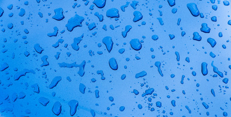 Rain drops on the blue car surface. Water srops on car hood. Water drops on blue metal surface.