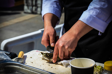 June 8, 2019, Gastronomic festival, Yekaterinburg, Russia: the chef opens oysters and pours lemon juice in the open air. Fresh and delicious seafood Breakfast.