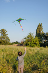 Little boy launches a kite in a summer park.
