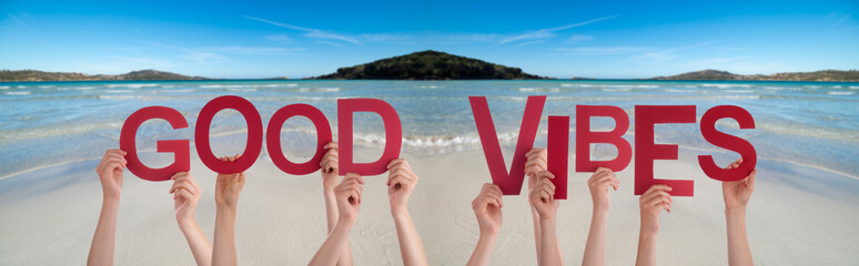 People Hands Holding Colorful English Word Good Vibes. Ocean And Beach As Background