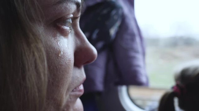 Upset Female With Tears In Eyes Looking Through Train Window. Close-up Side Portrait