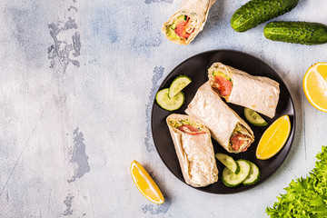 Wrapped sandwich with salmon, lettuce, cucumber and cream cheese.
