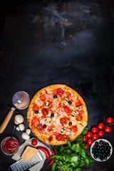 Traditional Italian pizza on a dark table with ingredients. Pizza menu. Space for text.