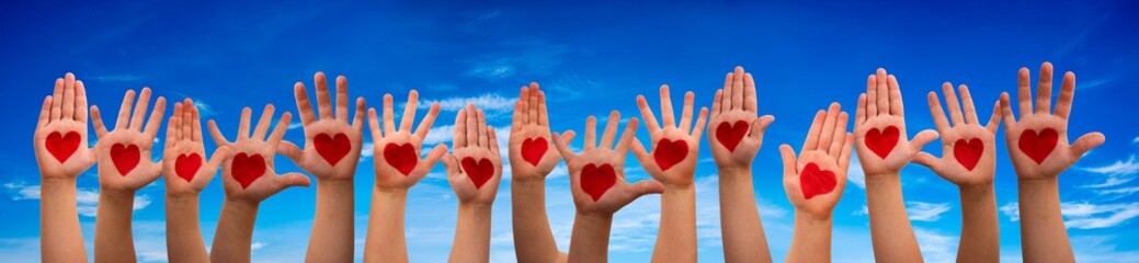 Many Children Hands Showing Red Heart Symbols. Blue Sky Background