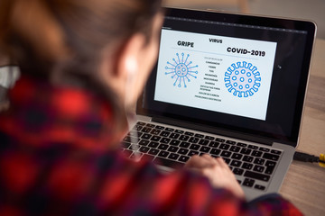 Young woman working from home due to the global pandemic. Web designer working on the corona virus, for a website about the global pandemic.