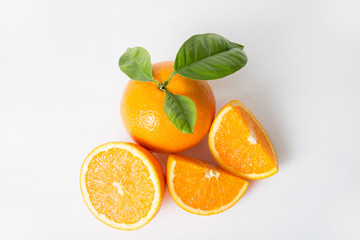 Cut and whole orange with green leaves isolated on white background. Closeup shot, top view. Natural vitamin or organic food concept