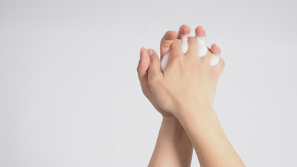 Male model is interlace fingers and continue rubbing with foaming hand soap on white background.