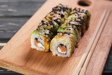 Sushi with salmon on a wooden board on a dark wooden background