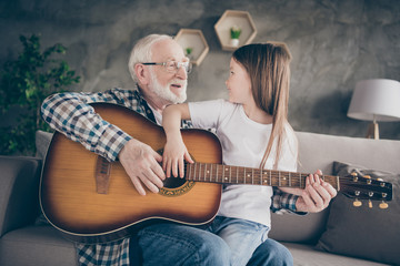 Photo of aged old grandpa little pretty granddaughter sitting comfy sofa playing guitar teaching...