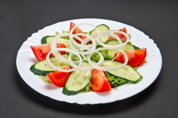 White ceramic plate with fresh cucumber, tomato and onion salad on grey background - 344143277
