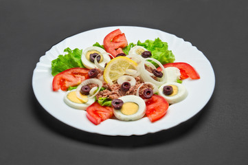 White ceramic plate with fresh tomatoes, onion, eggs, olives and fish salad on grey background - 344143424
