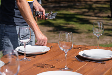 Girl the waiter in a summer cafe under the open sky arranges the dishes on a wooden banquet table.