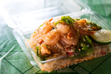 Fried rice topped with shrimp in a plastic box.