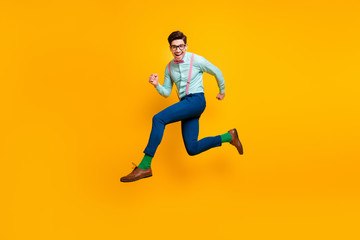Fototapeta na wymiar Full body profile photo of cool stylish guy jumping high up rejoicing rushing shopping center wear specs shirt bow tie suspenders trousers shoes green socks isolated yellow color background