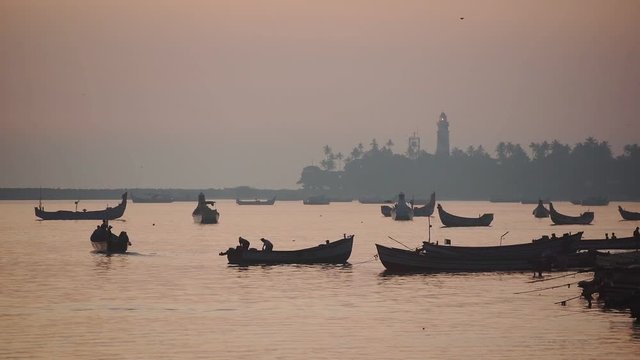 Landscape view of silhouettes of fishermen going fishing on their traditional boats, Kappil Beach, Varkala, India