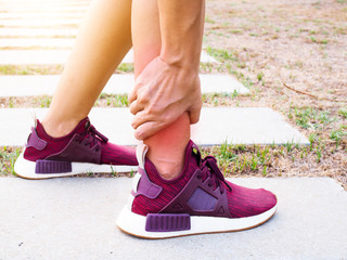 Asian women use hand touch and massage legs with ankle pain from outdoor exercise.