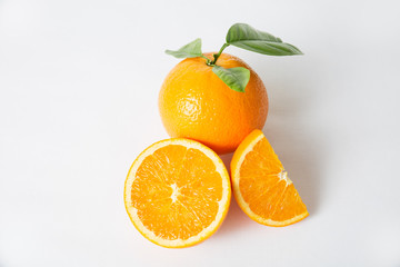 Cut juicy slices and whole orange with green leaves isolated on white background. Closeup shot. Natural vitamin or organic food concept