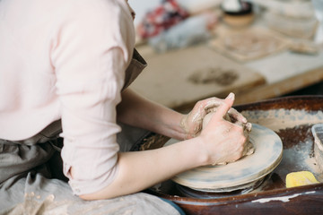 Girl making cup at potter's wheel closeup.