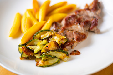 Roasted pork neck steak with vegetable and french fries.