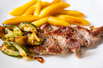 Roasted pork neck fillet with vegetable and french fries.