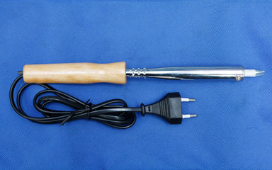 A close-up on a portable adjustable temperature electric soldering iron welding tool with a wooden...