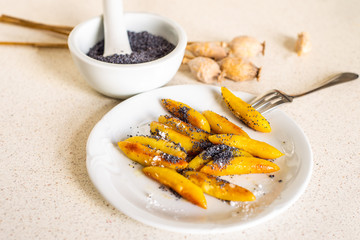 Sweet potato dumplings (wedges) with poppy seed, poppy heads, mortar.