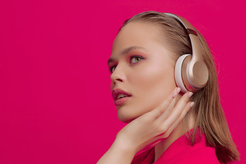 A beautiful young girl in wireless headphones listens to song with a good mood. bright colorful music poster.