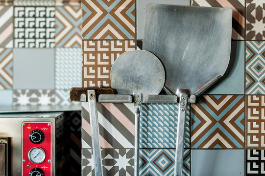 pizza tools weigh on the wall near the oven