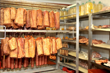 A worker at the meat processing factory, prepares sausages at the work table. Food processing and processing industry. Raw meat mix: steaks, poultry, sausages, ham, chopped, minced meat. The farm