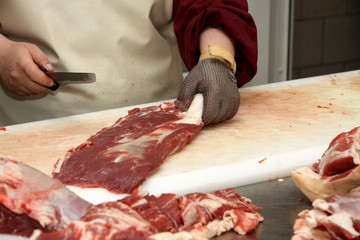 A worker at the meat processing factory, prepares sausages at the work table. Food processing and processing industry. Raw meat mix: steaks, poultry, sausages, ham, chopped, minced meat. The farm