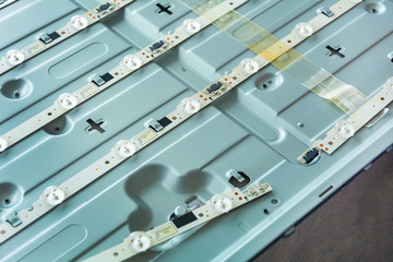 Torn LED circuit board on LED TV close-up, faulty TV, repair of LED circuit board in the center.