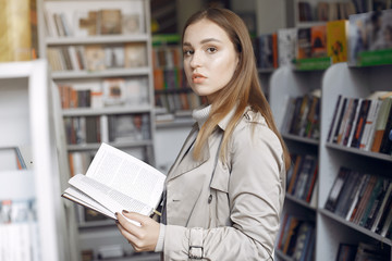 Girl in the library. Student looking for a book. Lady in a brown coat.