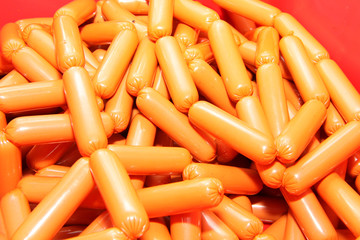 A worker at the meat processing factory, prepares sausages at the work table. Food processing and processing industry. Raw meat mix: steaks, poultry, sausages, ham, chopped, minced meat. The farm