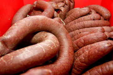 A worker at the meat processing factory, prepares sausages at the work table. Food processing and processing industry. Raw meat mix: steaks, poultry, sausages, ham, chopped, minced meat. The farm