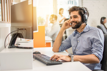 Smiling friendly handsome young male call centre operator.