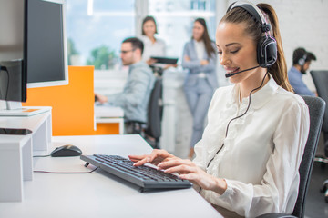 Portrait of female customer support or sales agent. Caller or receptionist phone operator working in call center. - obrazy, fototapety, plakaty